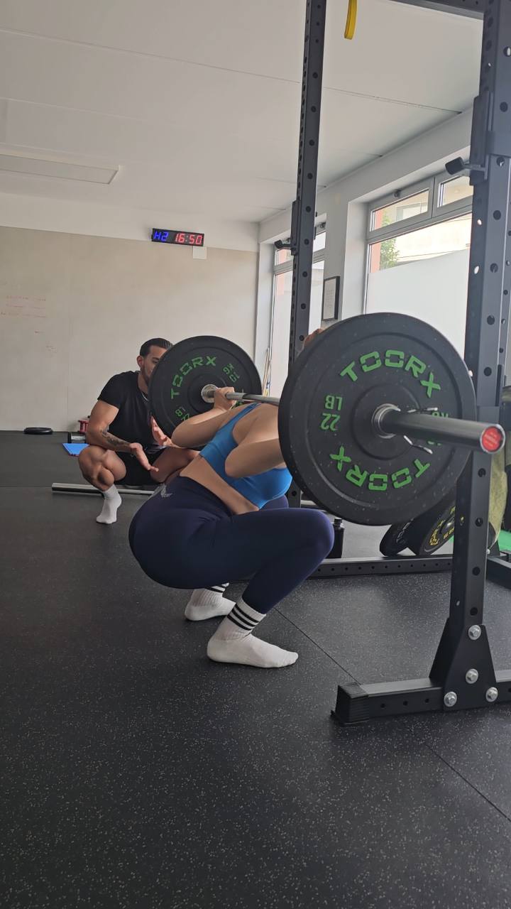 Atleta durante uno squat con Anthony Ciccarelli che osserva la tecnica