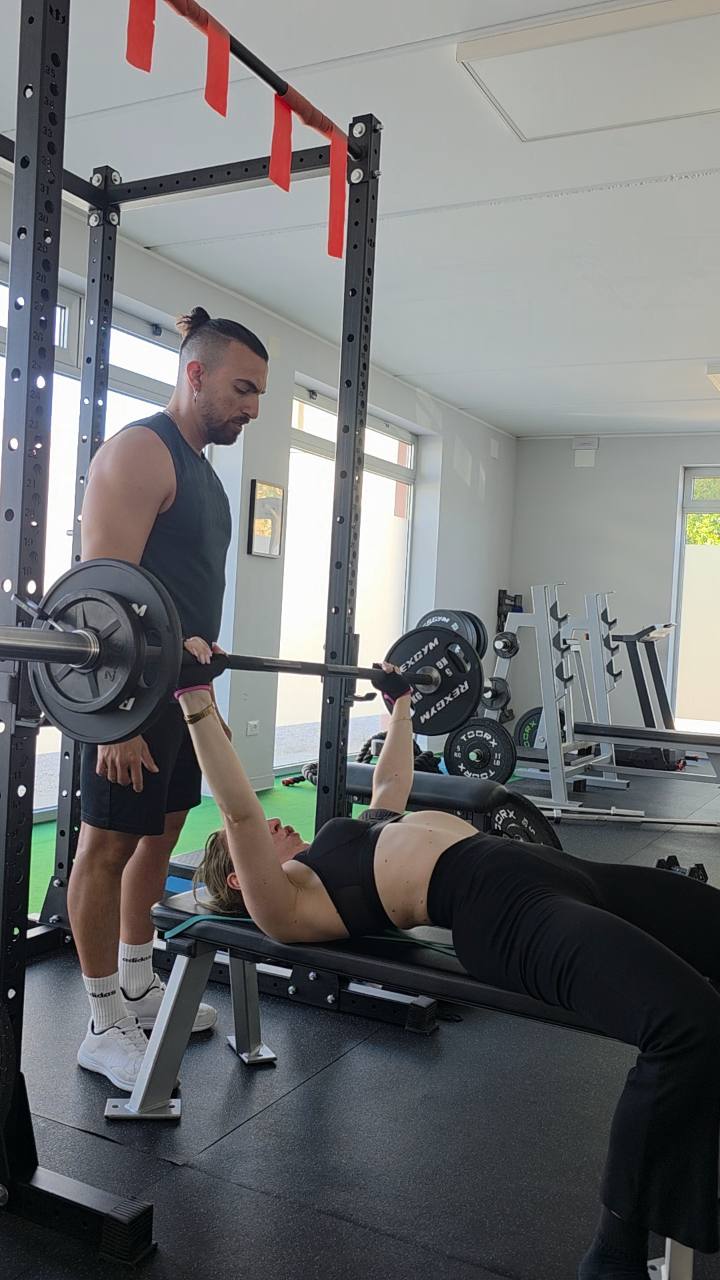 Atleta durante una distensione su panca con Anthony Ciccarelli in assistenza